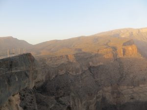 Sunset at Jebel Shams, warm orange light on the cliffs